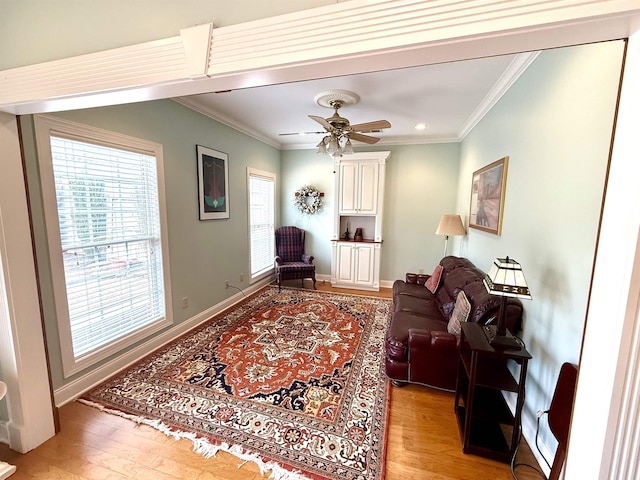 living room featuring light hardwood / wood-style flooring, ornamental molding, and ceiling fan