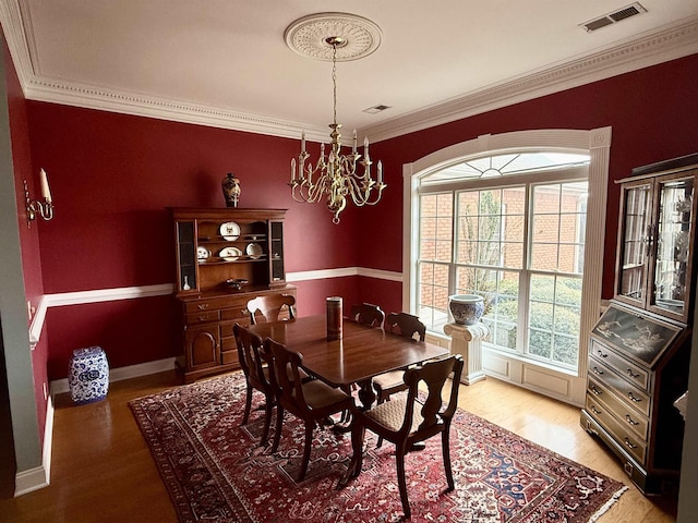 dining space with crown molding, an inviting chandelier, and light hardwood / wood-style floors