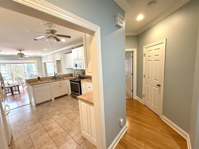 kitchen with sink, white cabinetry, ornamental molding, kitchen peninsula, and white appliances