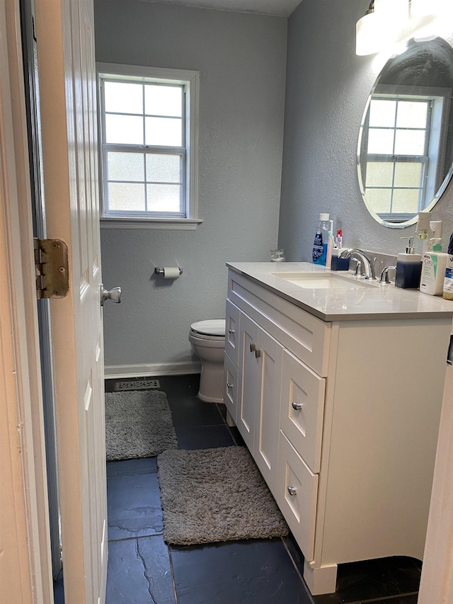 bathroom featuring vanity, a healthy amount of sunlight, and toilet