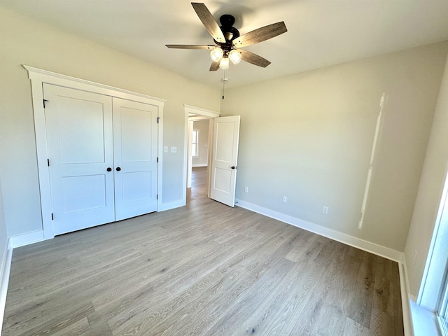 unfurnished bedroom featuring ceiling fan, light hardwood / wood-style floors, and a closet