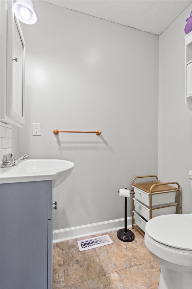  - bathroom featuring toilet, vanity, and baseboards