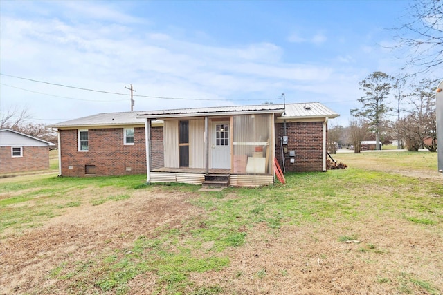  - back of house with brick siding, a lawn, and metal roof