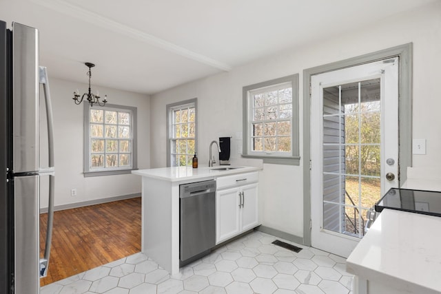 kitchen with decorative light fixtures, white cabinetry, sink, kitchen peninsula, and stainless steel appliances