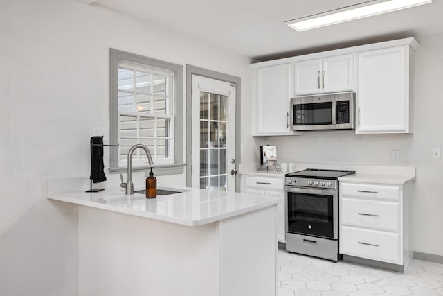 kitchen featuring stainless steel appliances, white cabinetry, and kitchen peninsula