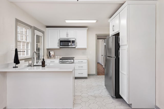 kitchen with white cabinetry, appliances with stainless steel finishes, kitchen peninsula, and sink