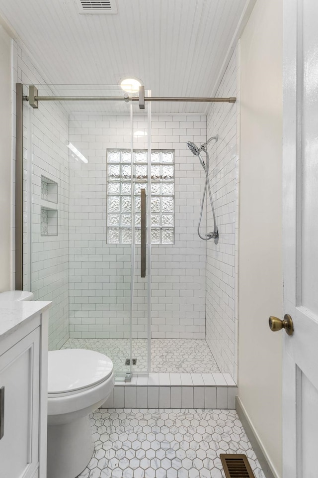 bathroom with toilet, vanity, tile patterned floors, and a shower with shower door