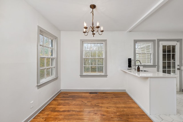 unfurnished dining area with sink, a chandelier, and dark hardwood / wood-style floors