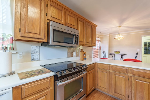  - kitchen featuring appliances with stainless steel finishes, light countertops, brown cabinets, hanging light fixtures, and ornamental molding