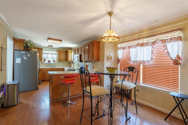  - kitchen featuring stainless steel appliances, ornamental molding, a chandelier, light countertops, and light wood-style flooring