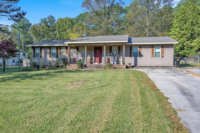 ranch-style home with driveway, covered porch, fence, and a front yard