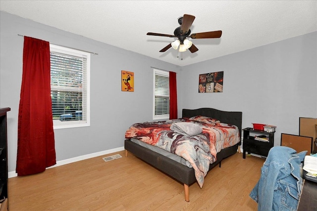 bedroom with ceiling fan, a textured ceiling, and light hardwood / wood-style flooring