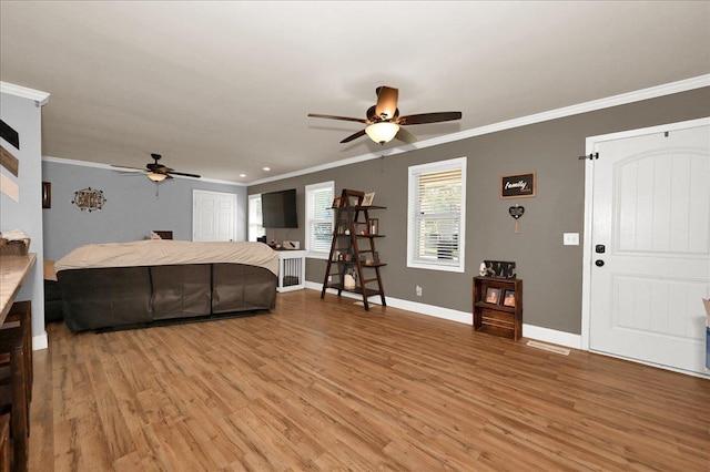 living room with light wood finished floors, a ceiling fan, crown molding, and baseboards