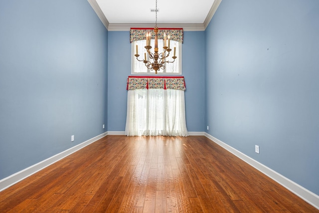 empty room with hardwood / wood-style floors, an inviting chandelier, and crown molding