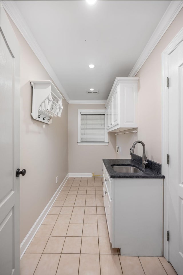 kitchen featuring white cabinetry, sink, light tile patterned floors, and crown molding