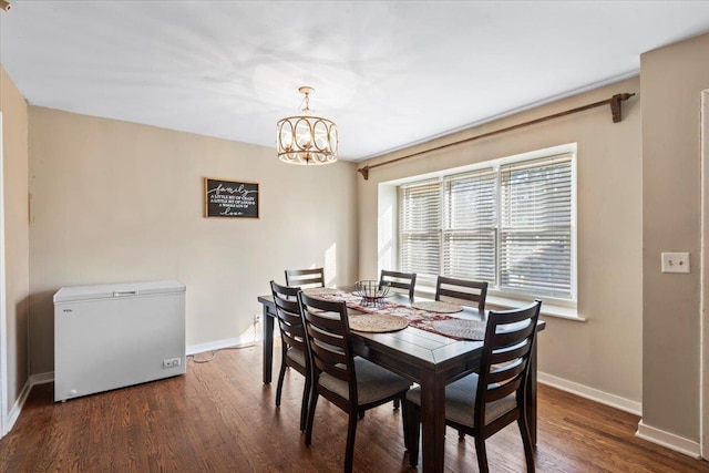 dining room with dark wood-type flooring and a notable chandelier