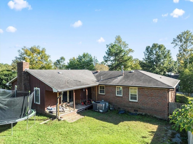 rear view of house with a yard, a trampoline, and a patio