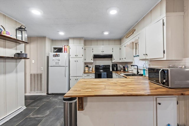 kitchen with black electric range oven, white refrigerator, sink, white cabinetry, and kitchen peninsula