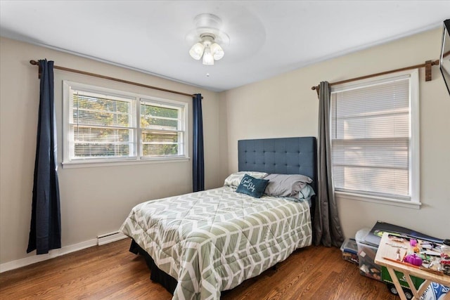 bedroom with ceiling fan, a baseboard radiator, and hardwood / wood-style flooring