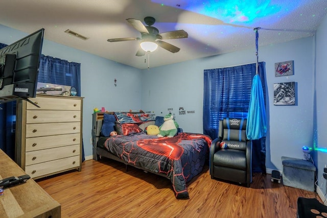 bedroom featuring hardwood / wood-style flooring, ceiling fan, and a textured ceiling