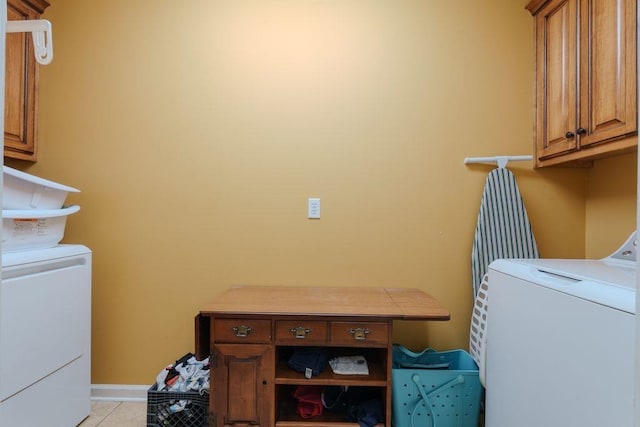 laundry area with washing machine and clothes dryer, light tile patterned flooring, and cabinets