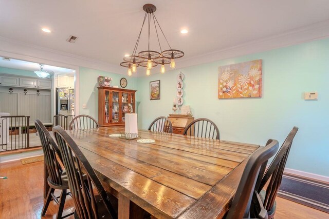 dining room featuring a chandelier, light hardwood / wood-style floors, and ornamental molding