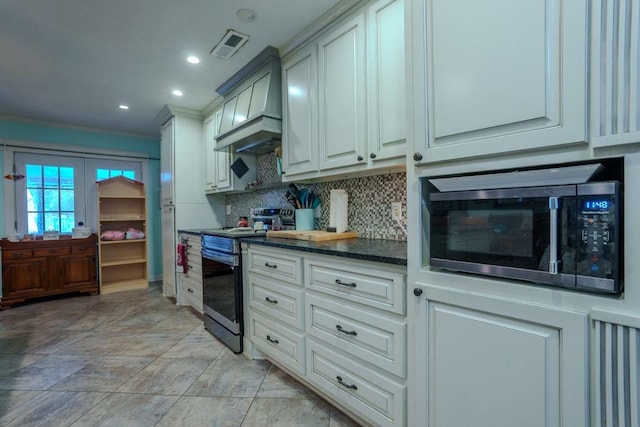 kitchen featuring dark stone counters, french doors, appliances with stainless steel finishes, tasteful backsplash, and custom range hood