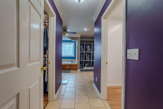 corridor with light tile patterned flooring, ornamental molding, and sink