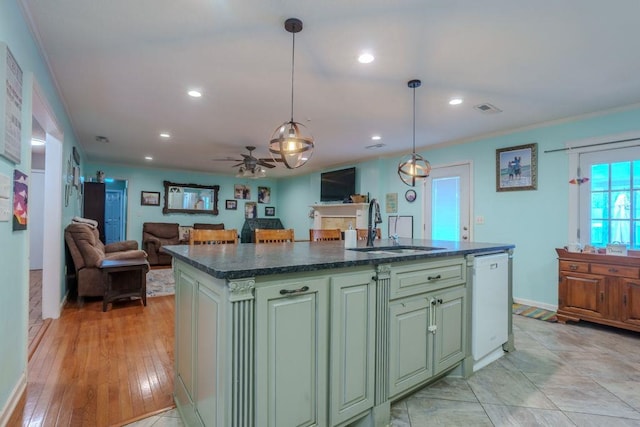 kitchen with ceiling fan, sink, hanging light fixtures, white dishwasher, and a center island with sink