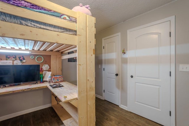 bedroom featuring built in desk, dark wood-type flooring, and a textured ceiling