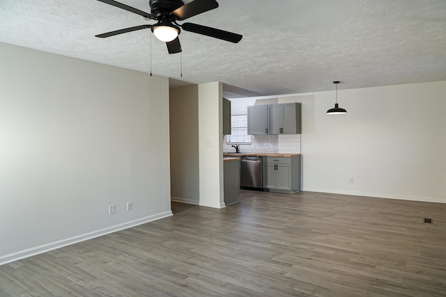 unfurnished living room with baseboards, a textured ceiling, wood finished floors, and a ceiling fan