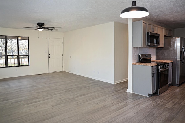 kitchen with tasteful backsplash, baseboards, light countertops, wood finished floors, and stainless steel appliances