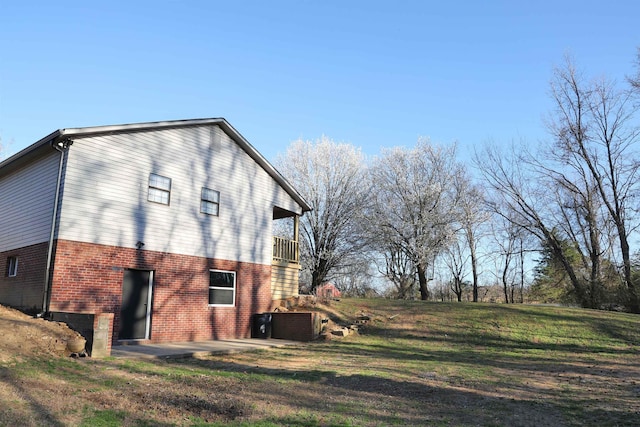 view of side of home with brick siding, central air condition unit, a patio area, and a lawn