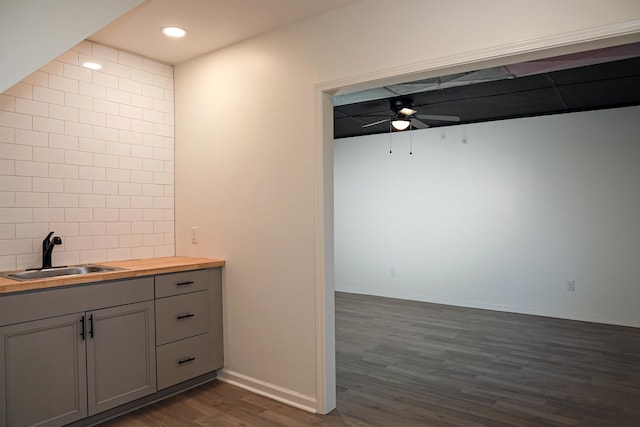 kitchen featuring wooden counters, gray cabinetry, dark wood finished floors, a ceiling fan, and a sink