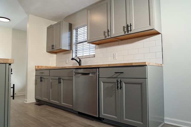 kitchen featuring gray cabinets, butcher block counters, and stainless steel dishwasher