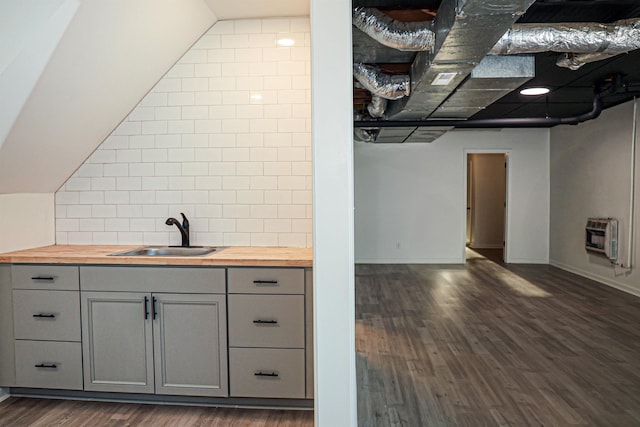 bar featuring a sink, decorative backsplash, heating unit, and dark wood-style flooring