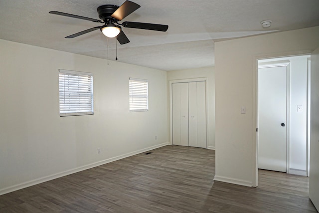 unfurnished bedroom featuring ceiling fan, baseboards, wood finished floors, a closet, and a textured ceiling