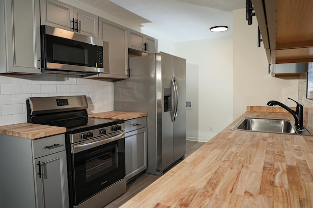 kitchen with a sink, gray cabinetry, appliances with stainless steel finishes, and butcher block countertops