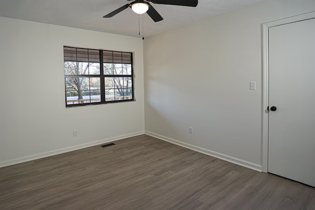 spare room featuring visible vents, dark wood-type flooring, a ceiling fan, a textured ceiling, and baseboards