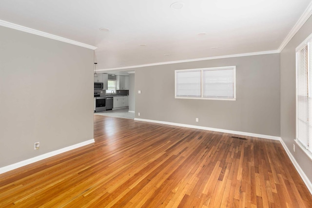 unfurnished living room featuring baseboards, ornamental molding, light wood-style flooring, and a sink