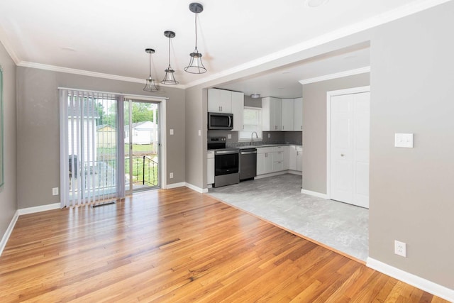 unfurnished living room featuring baseboards, ornamental molding, light wood-style floors, and a sink