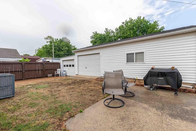 view of yard with a detached garage, fence, and cooling unit
