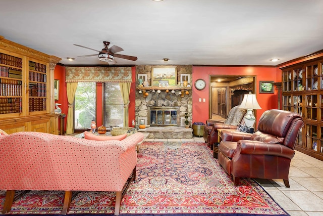 living room with ceiling fan, a fireplace, light tile patterned floors, and ornamental molding