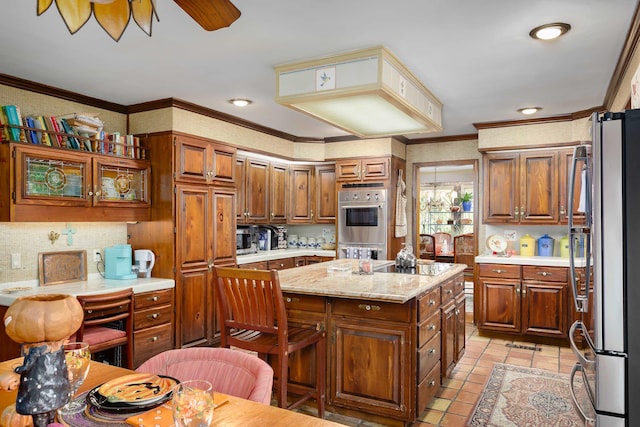 kitchen featuring light stone countertops, appliances with stainless steel finishes, a center island, and ornamental molding