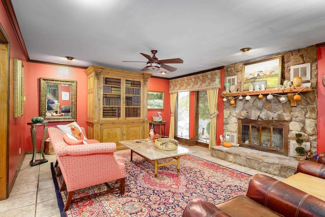 tiled living room featuring ceiling fan, a stone fireplace, and crown molding