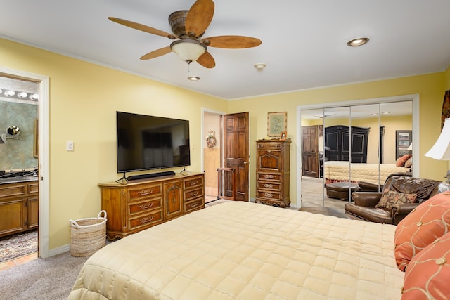 carpeted bedroom with connected bathroom, ceiling fan, a closet, and crown molding