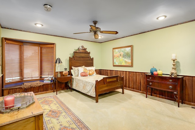 carpeted bedroom with ceiling fan, crown molding, and wooden walls