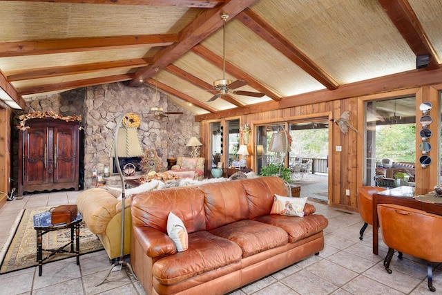 living room with ceiling fan, vaulted ceiling with beams, a stone fireplace, wooden walls, and light tile patterned floors