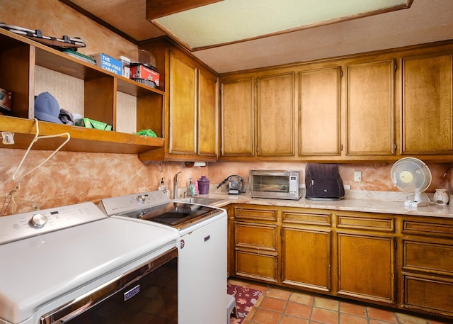 clothes washing area featuring washer and dryer, cabinets, light tile patterned floors, and sink