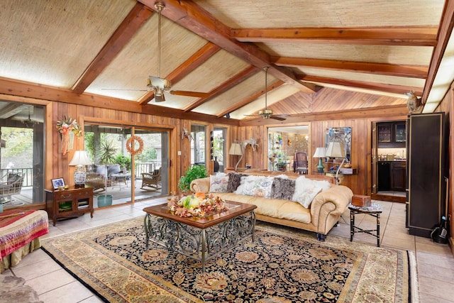 living room with vaulted ceiling with beams, wood walls, light tile patterned floors, and ceiling fan